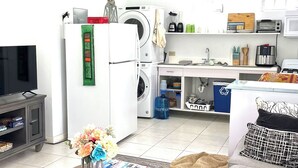 Een knus woongedeelte met een bank, salontafel, televisie, wasmachine en een keukenhoek.
