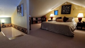 Ein Schlafzimmer mit einem großen Bett, zwei Nachttischen mit Lampen, einem Bücherregal und einem Himmel.