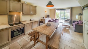 A kitchen with a central island, a dining area with a bench, and a view of the outdoors through a large sliding door. - Lovely home in Saint-Laurent-de-la-Ca with WiFi (Saint-Laurent-de-la-Ca)