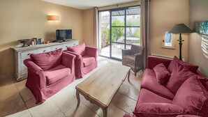 A living room with two red sofas, a wooden coffee table, a television on a cabinet, and a view of the outdoors through large windows. - Lovely home in Saint-Laurent-de-la-Ca with WiFi (Saint-Laurent-de-la-Ca)
