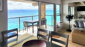 Ein Balkon mit Tisch und Stühlen, einem Ventilator und Blick auf das Meer.