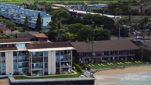 Ein Hotel direkt am Strand mit mehreren Etagen, einem Poolbereich und einer Liegewiese mit Liegestühlen.