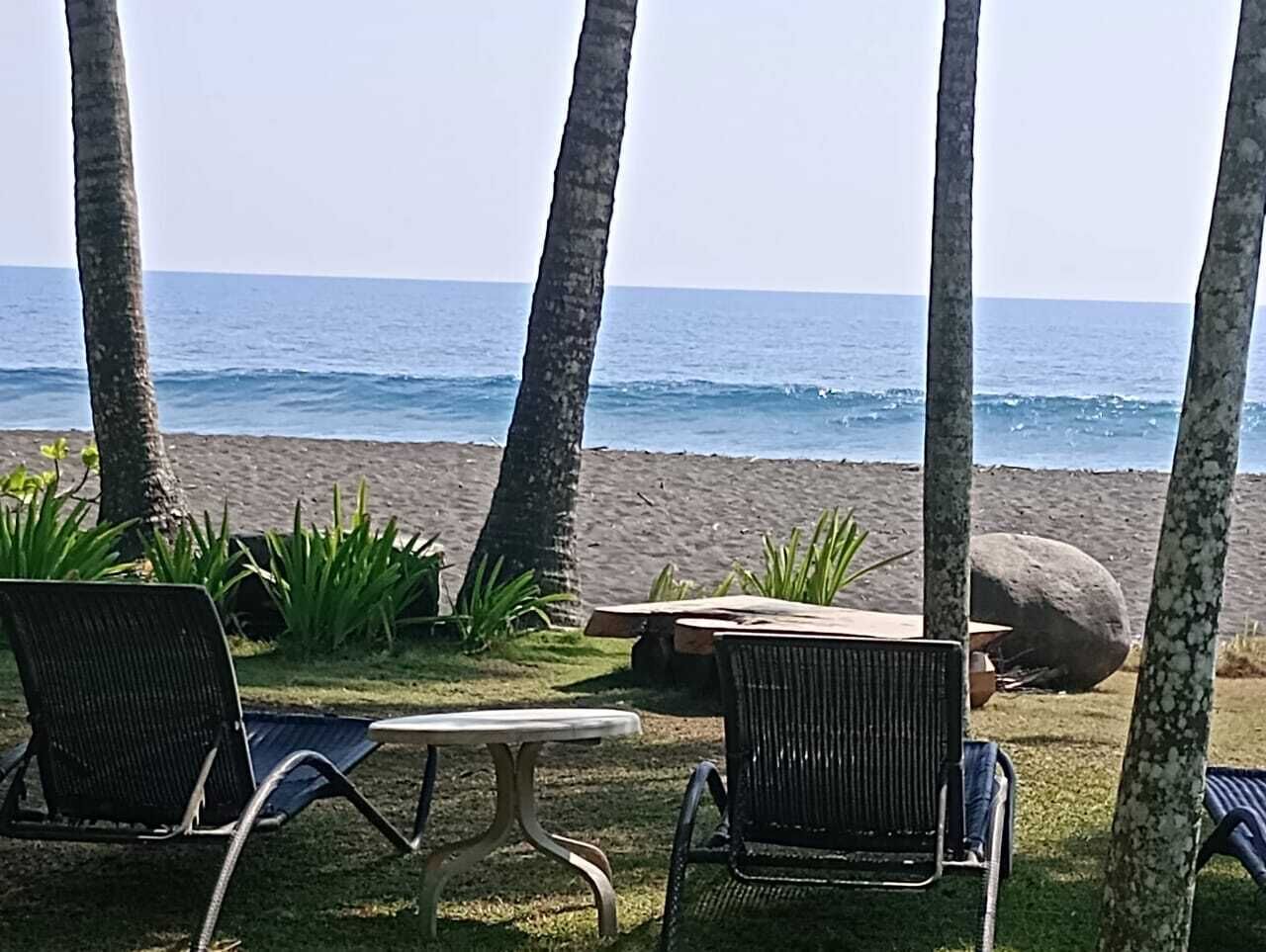 A beachside seating area with chairs and a table, overlooking the ocean.