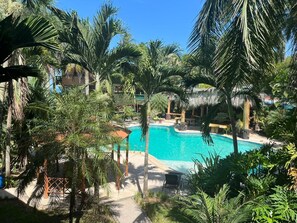 Una piscina rodeada de palmeras y una estructura con techo de paja.