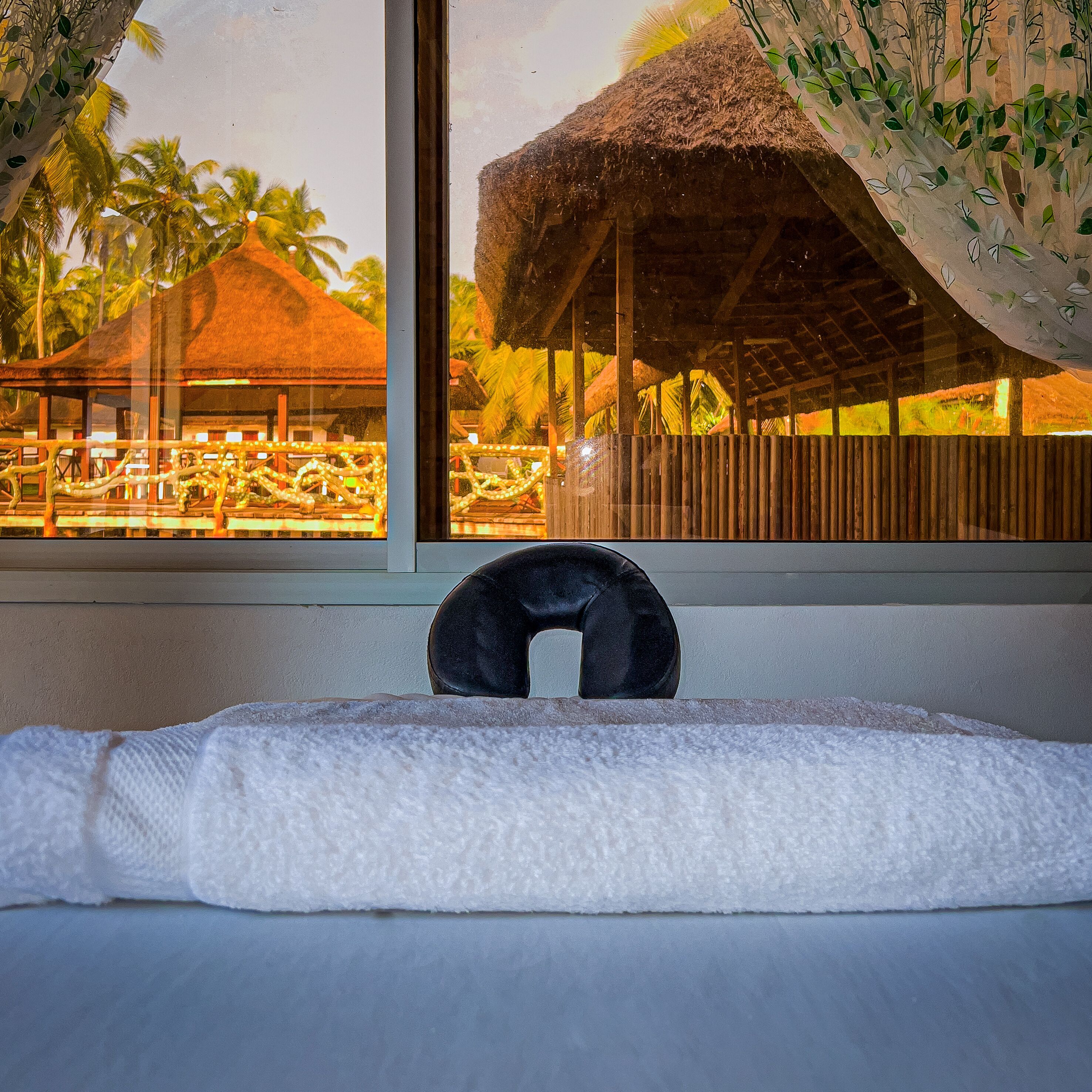 Habitación de hotel con vista a una estructura de techo de paja y palmeras.