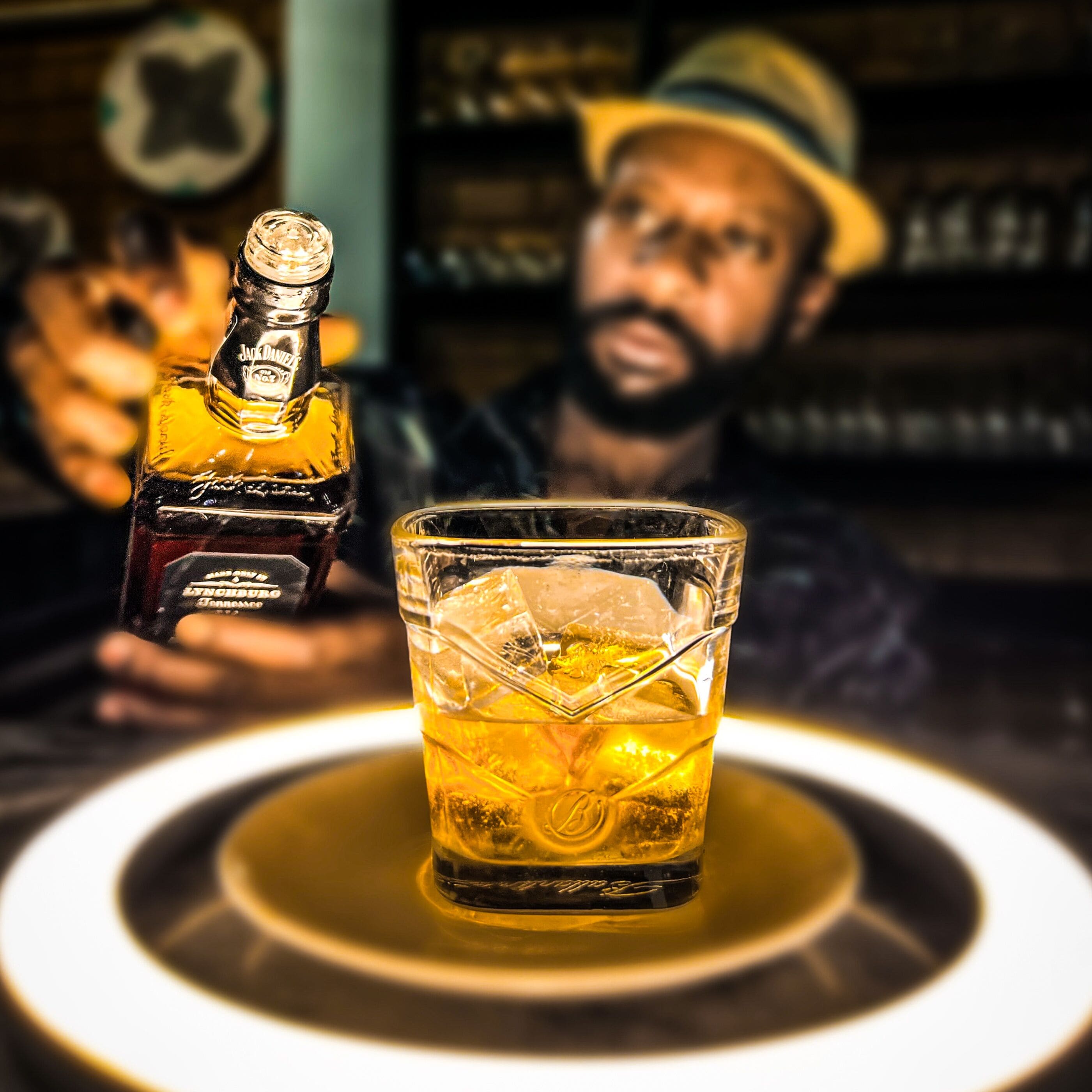 Una botella de whiskey Jack Daniel's y un vaso con hielo sobre una mesa.