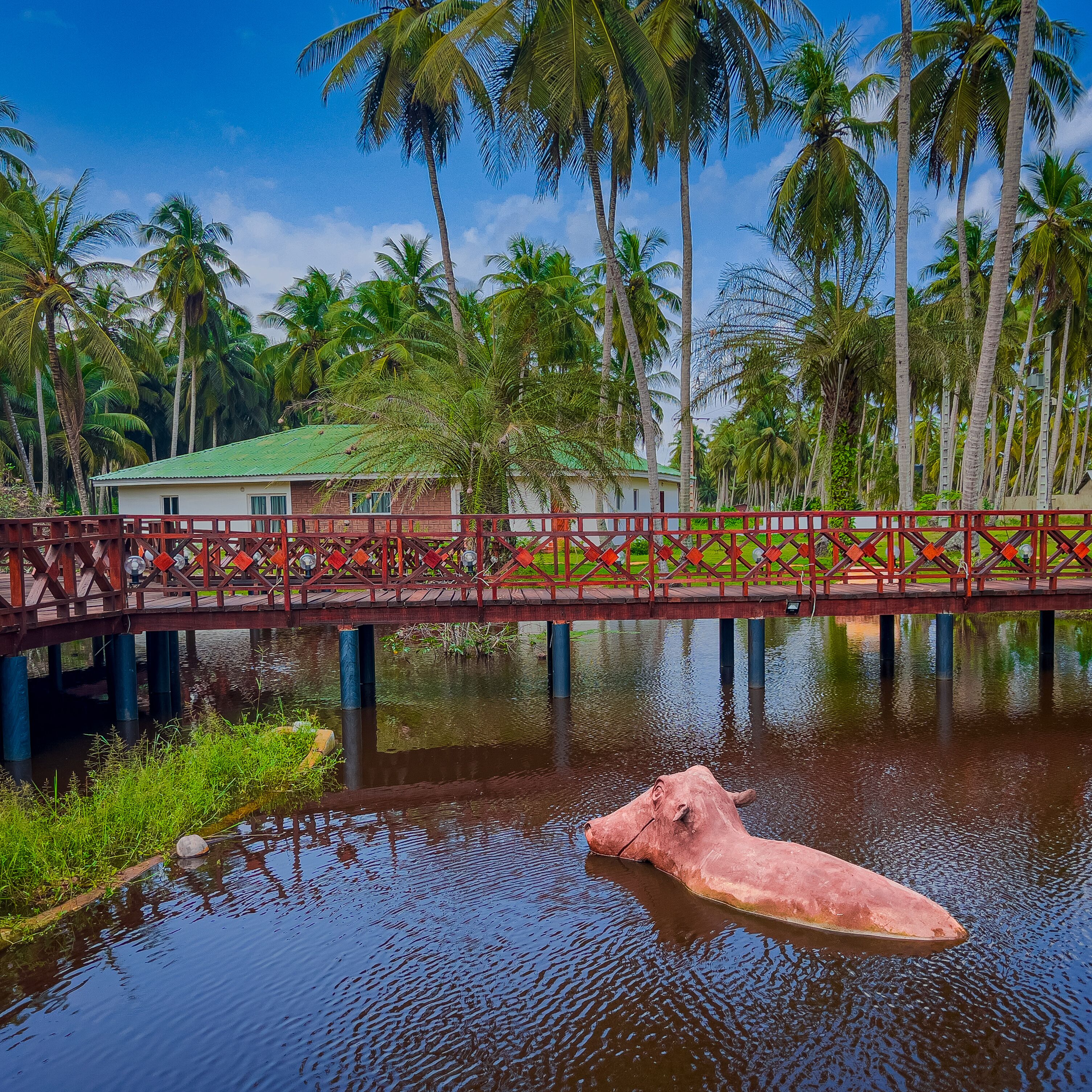 A bridge over a calm body of water with a large pink sculpture in the foreground.