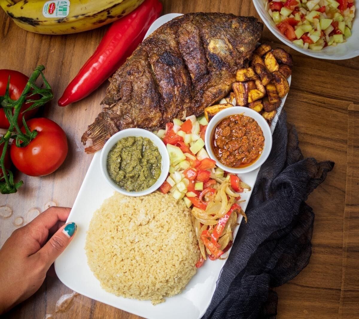 A plate with grilled fish, rice, and various side dishes.