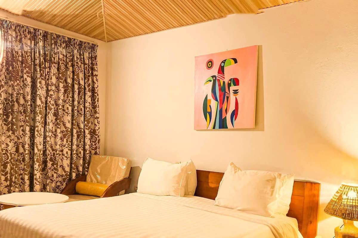 A neatly made bed with white linens, a wooden headboard, and a bedside table with a lamp and phone.