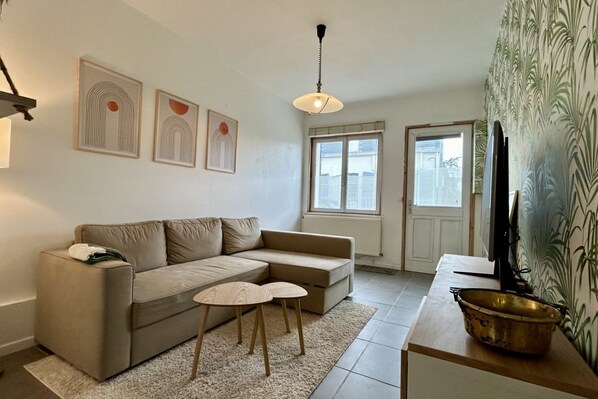 A living room with a sofa, a small table, a television, and artwork on the wall.