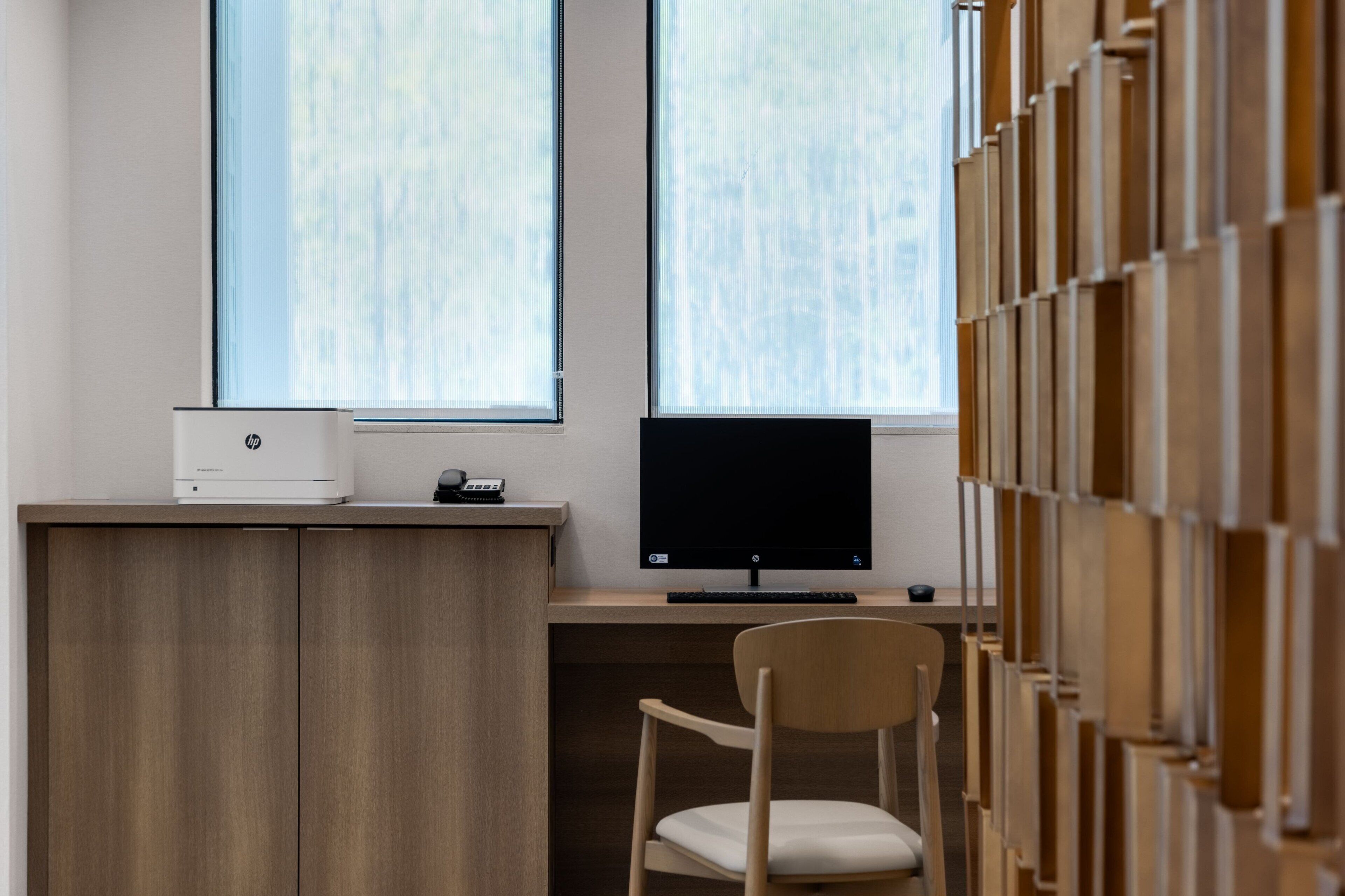 Ein moderner Arbeitsplatz mit Schreibtisch, zwei Monitoren, einem Drucker und einem Stuhl.