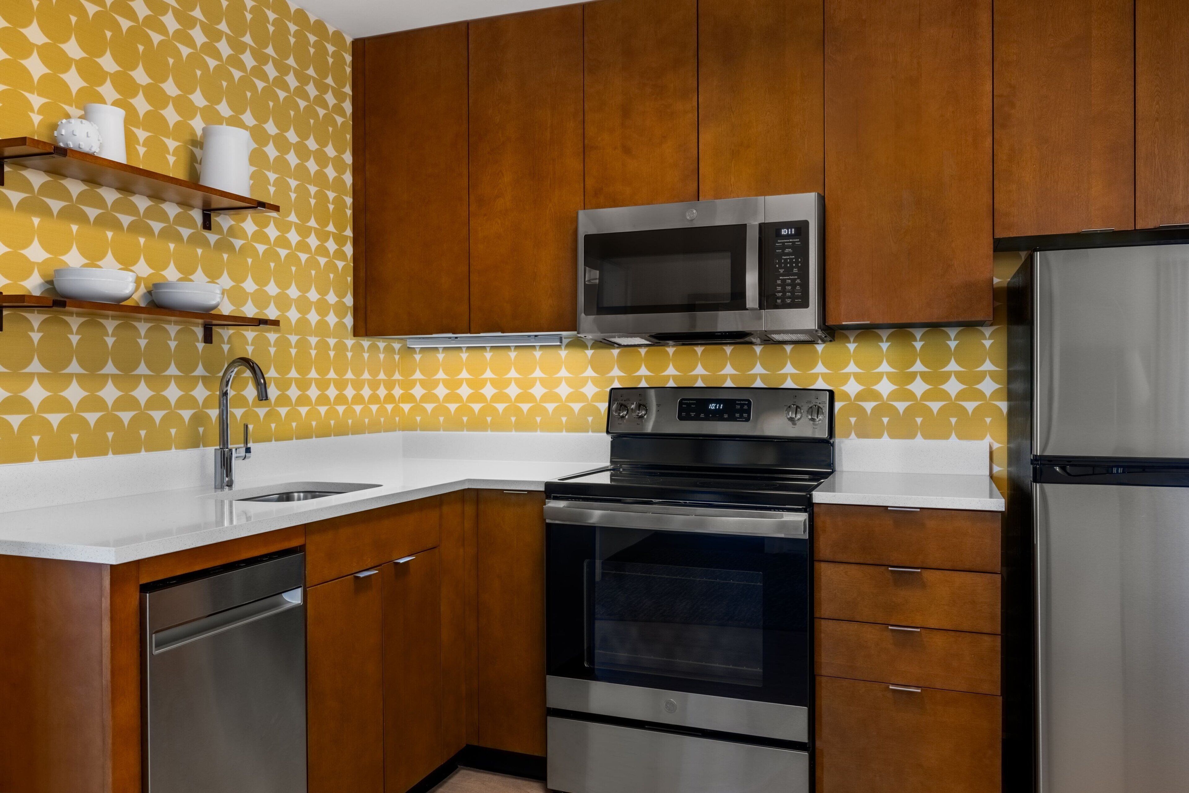 A kitchen with wooden cabinets, a stainless steel microwave, oven, and dishwasher.