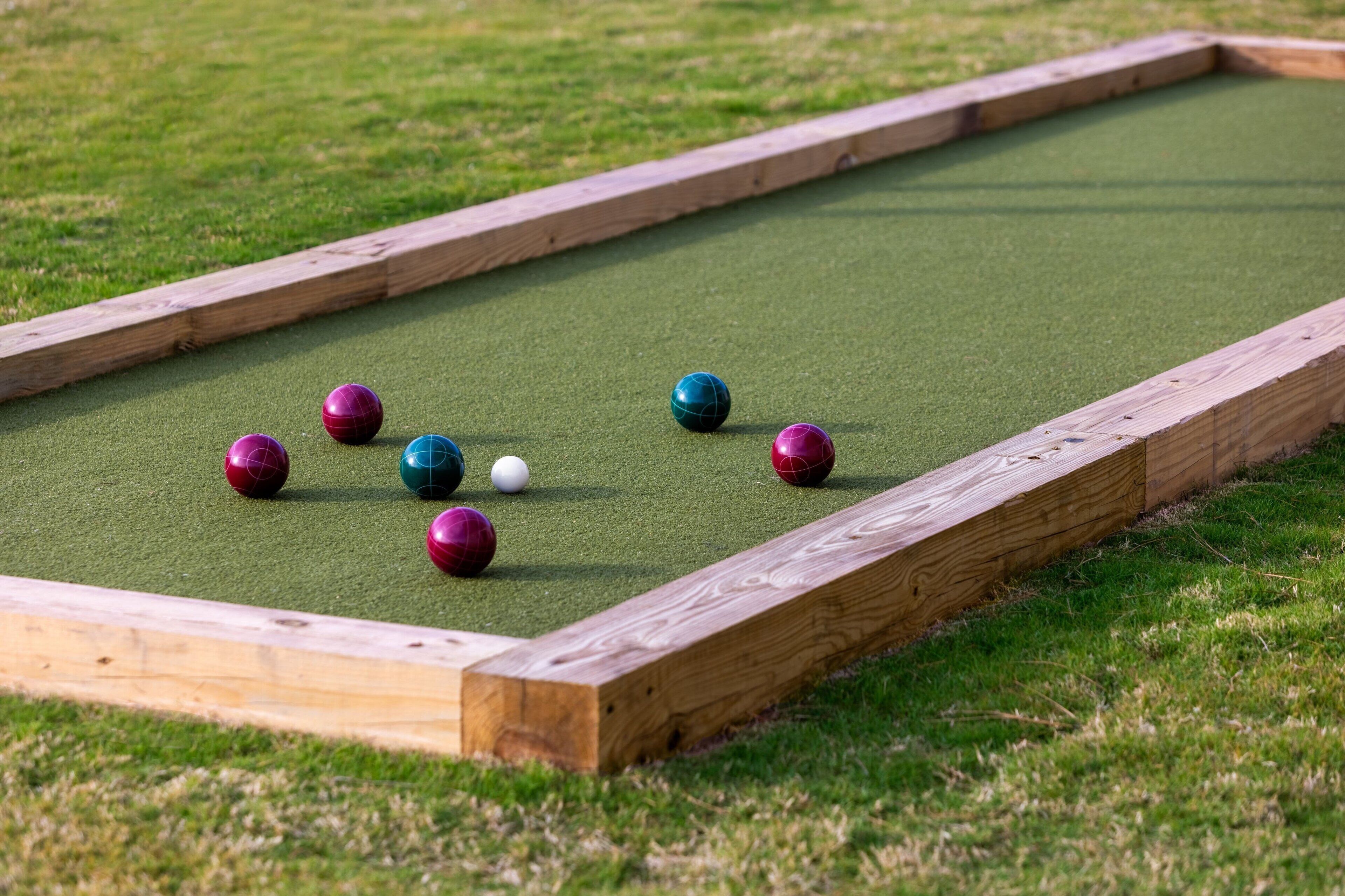 A croquet court with a wooden frame and green artificial turf.
