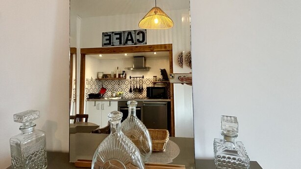 A kitchen with a sign that reads 'CAFE,' a hanging light fixture, and three glass decanters on a table. - Belle Échappée, Expérience Unique, Alliant Charme Historique, Commodités Moderne (Le Crotoy)