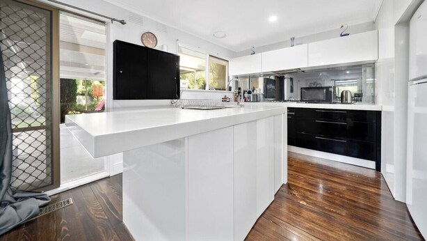 A modern kitchen with white cabinetry, a black countertop, and a wooden floor. - FamParadise: Pool, Cabin, Garden, Peace & More ! (Berwick)