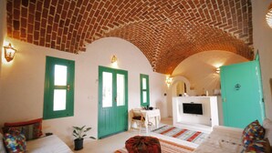 A cozy living room with a high, arched brick ceiling, a fireplace, and a television. - Bangalow Chebba (LA CHEBBA)