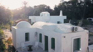A white, dome-shaped building with a patio area, including a table and chairs, surrounded by natural vegetation. - Bangalow Chebba (LA CHEBBA)