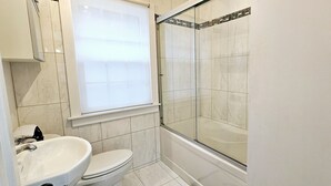 A bathroom with a toilet, sink, and glass shower enclosure.