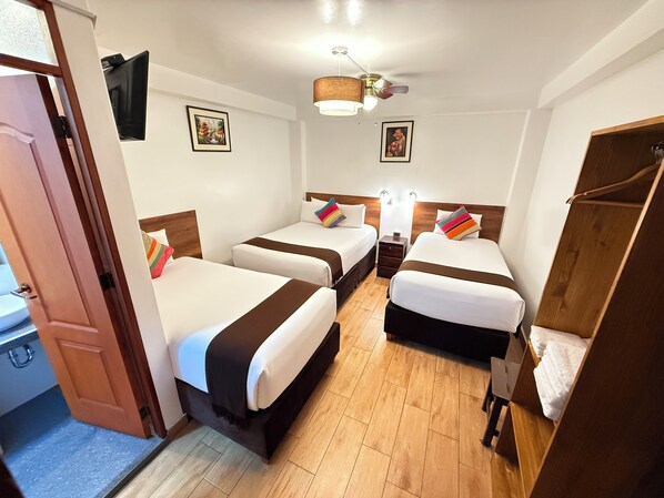 A hotel room with two beds, a wooden wardrobe, a ceiling fan, and a TV mounted on the wall. - Inti Pacha Palace Machupicchu (Machu Picchu)