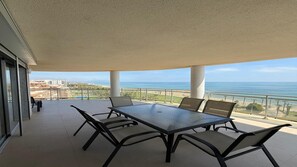 A balcony with a table and chairs, overlooking a beach and ocean. - Edificio Mondrian, 1ª Línea de Playa, Frontal de Esquina. Servhouse (Orpesa)