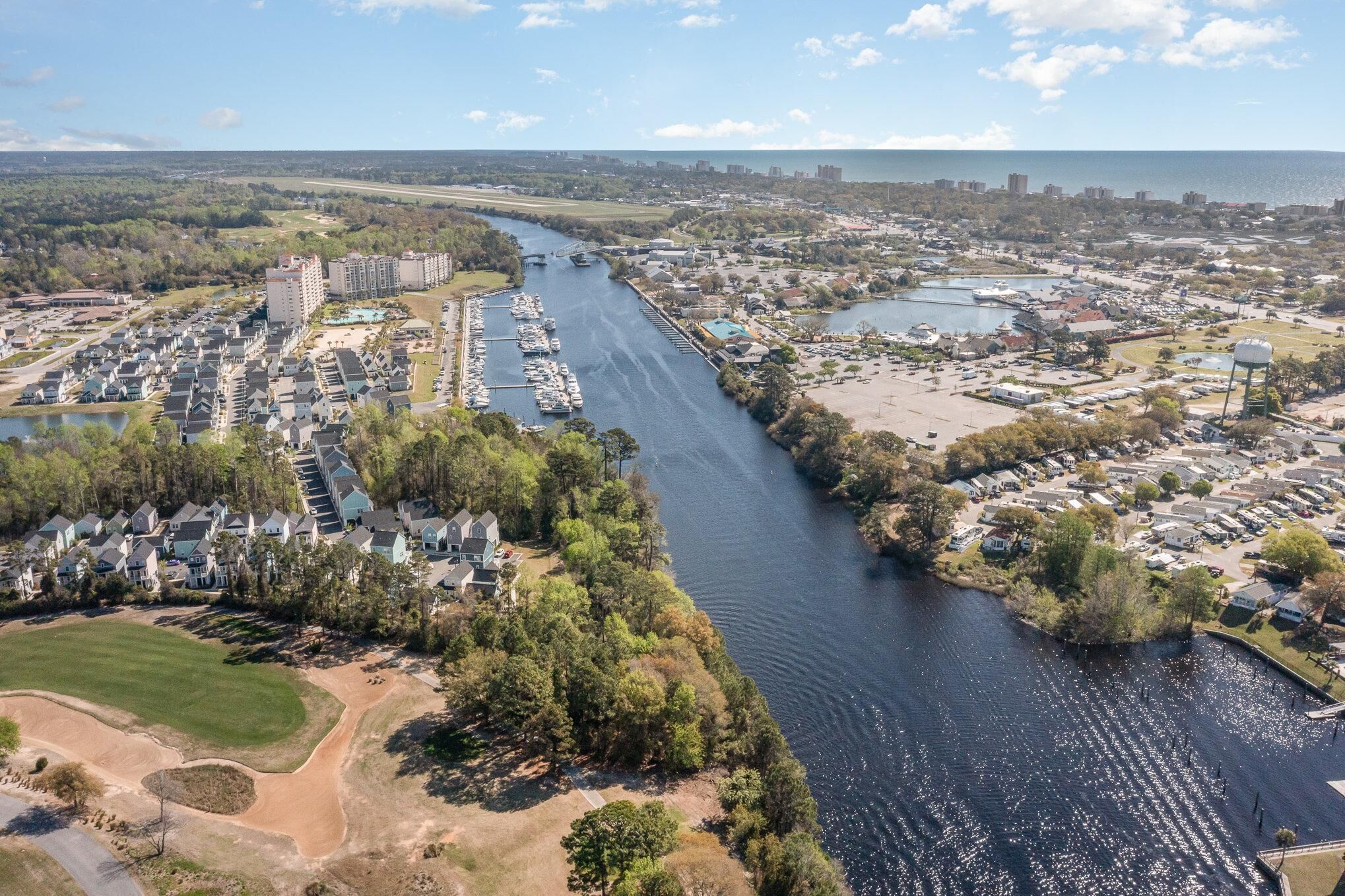 An aerial view of a coastal residential area with a marina, houses, and a large body of water.