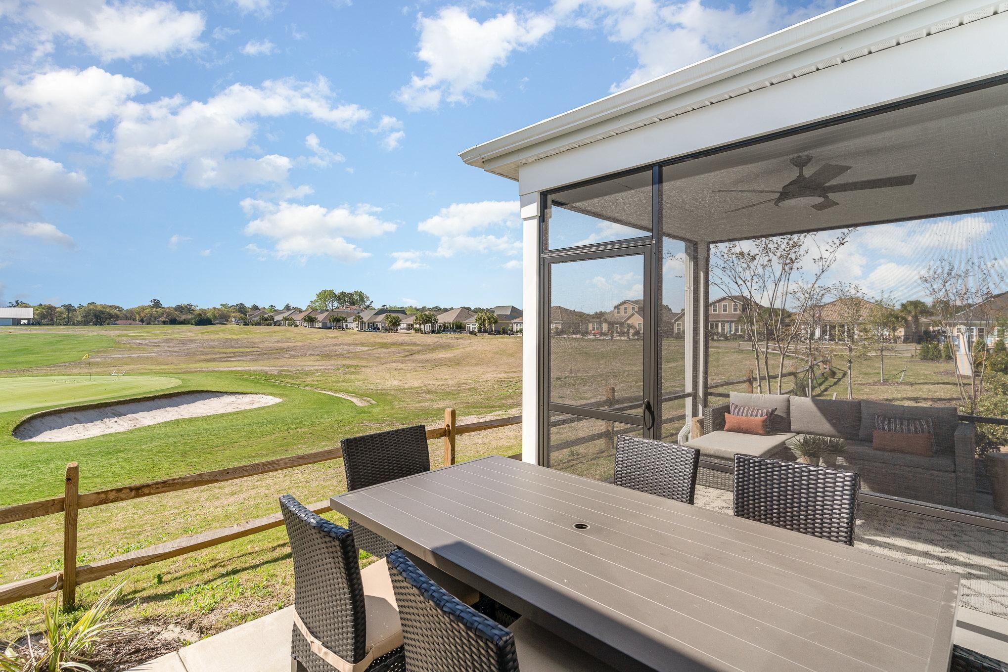 Une terrasse couverte, dotée d’une table et de chaises, qui offre une vue sur un terrain de golf.