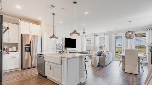 A modern kitchen with white cabinetry, stainless steel appliances, and pendant lighting.