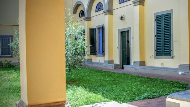 Um edifício com fachada amarela, janelas em arco e porta verde.