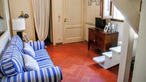 Uma sala de estar acolhedora com um sofá listrado, um armário de madeira e uma escada branca.