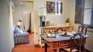 Uma área de refeições acolhedora com uma mesa de madeira, cadeiras e um sofá listrado.