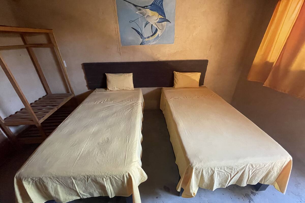 Une chambre avec deux lits simples, une étagère en bois et un tableau au mur.