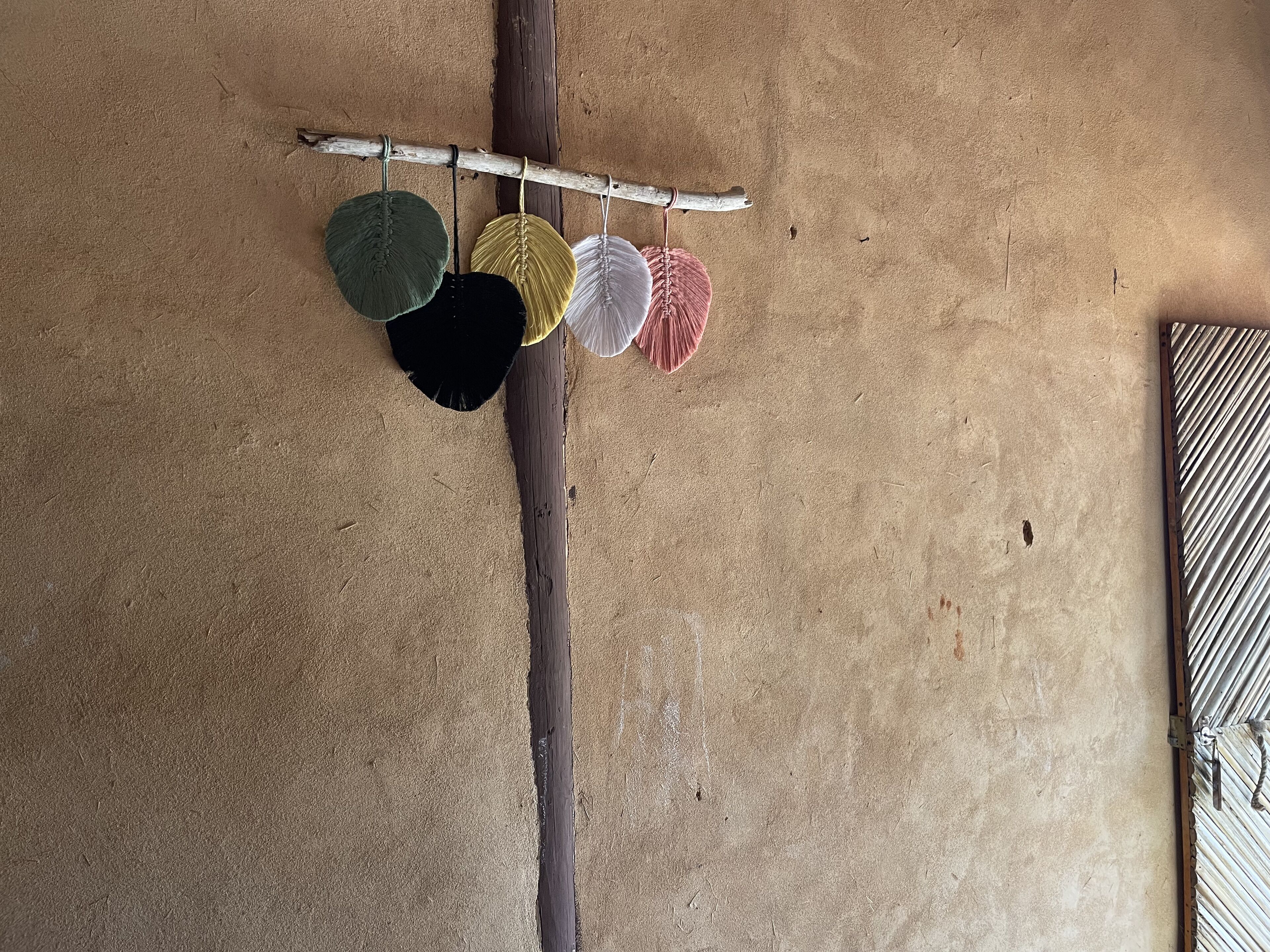 Una trave di legno con quattro oggetti appesi su un muro strutturato.