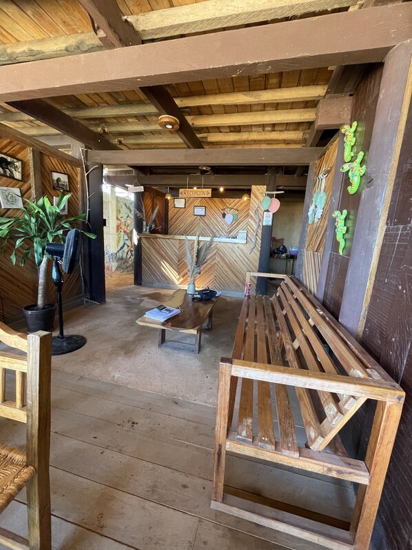 A reception area with wooden benches, a reception desk, and a wall with a herringbone pattern. - Okansi Cabaña (Marquelia)