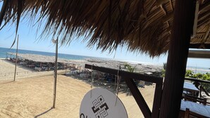 Uitzicht op een strand met een constructie met rieten dak en een bord waarop 