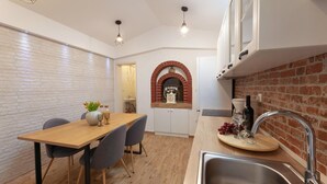 A modern kitchen with a wooden table, two chairs, a brick backsplash, and a built-in oven. - Stunning home in Kastel Novi (Kastel Novi)