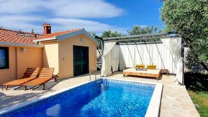 A swimming pool with lounge chairs, a bed with white curtains, and a building with a tiled roof. - Stunning home in Kastel Novi (Kastel Novi)