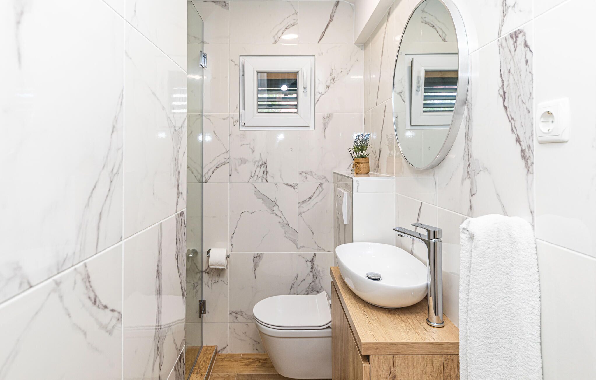 A modern bathroom with a toilet, sink, and shower.