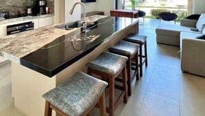 Una cucina moderna con isola centrale, sgabelli da bar, una ventola a soffitto e un'ampia finestra vista all'esterno.