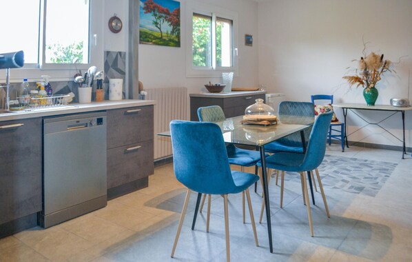 Una cocina moderna con una mesa de comedor de vidrio, sillas azules y vistas al exterior por una ventana.