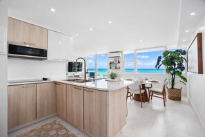 Een moderne keuken met een groot eiland, een eethoek met uitzicht op de oceaan en een grote potplant.