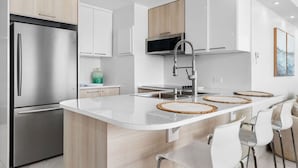 A modern kitchen with a stainless steel refrigerator, white cabinets, a central island with woven placemats, and a stainless steel faucet. - Beachfront Sanctuary Newly Renovated to Perfection with Full Power Generator (Carolina)