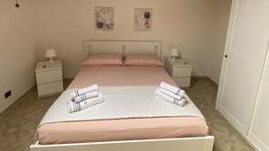 A bedroom with a skylight, wooden ceiling beams, a bed with pink bedding, two bedside tables with lamps, and artwork on the wall. - Detached house and outdoor terrace (Palermo)