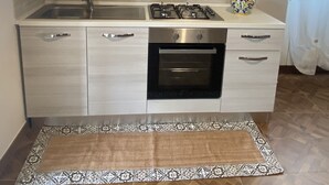 A modern kitchen with light wood cabinets, stainless steel appliances, and a patterned rug. - Detached house and outdoor terrace (Palermo)
