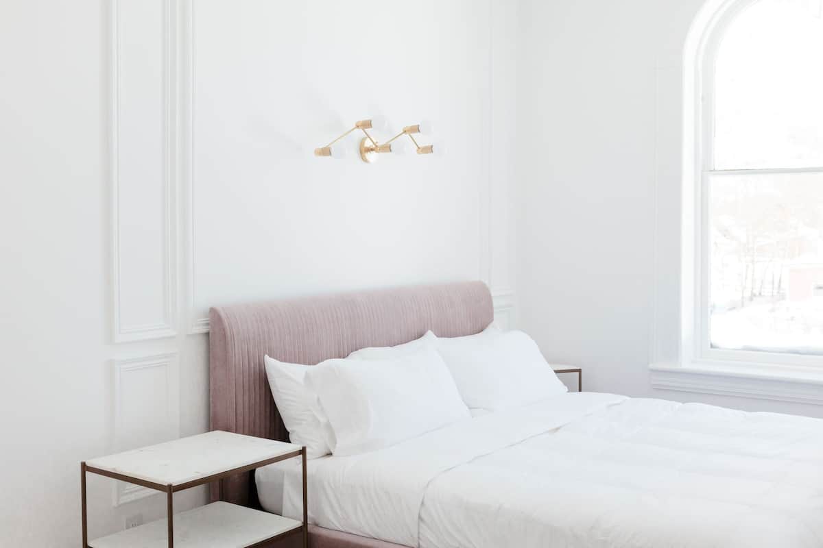 A bedroom with a bed, a nightstand, and a wall-mounted light fixture.