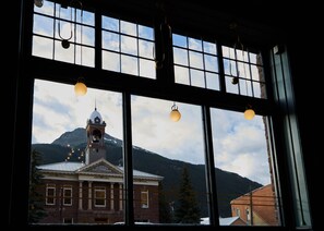 A view through a window with a bell tower, a building with columns, and mountains in the background. - The Wyman Hotel (Silverton)