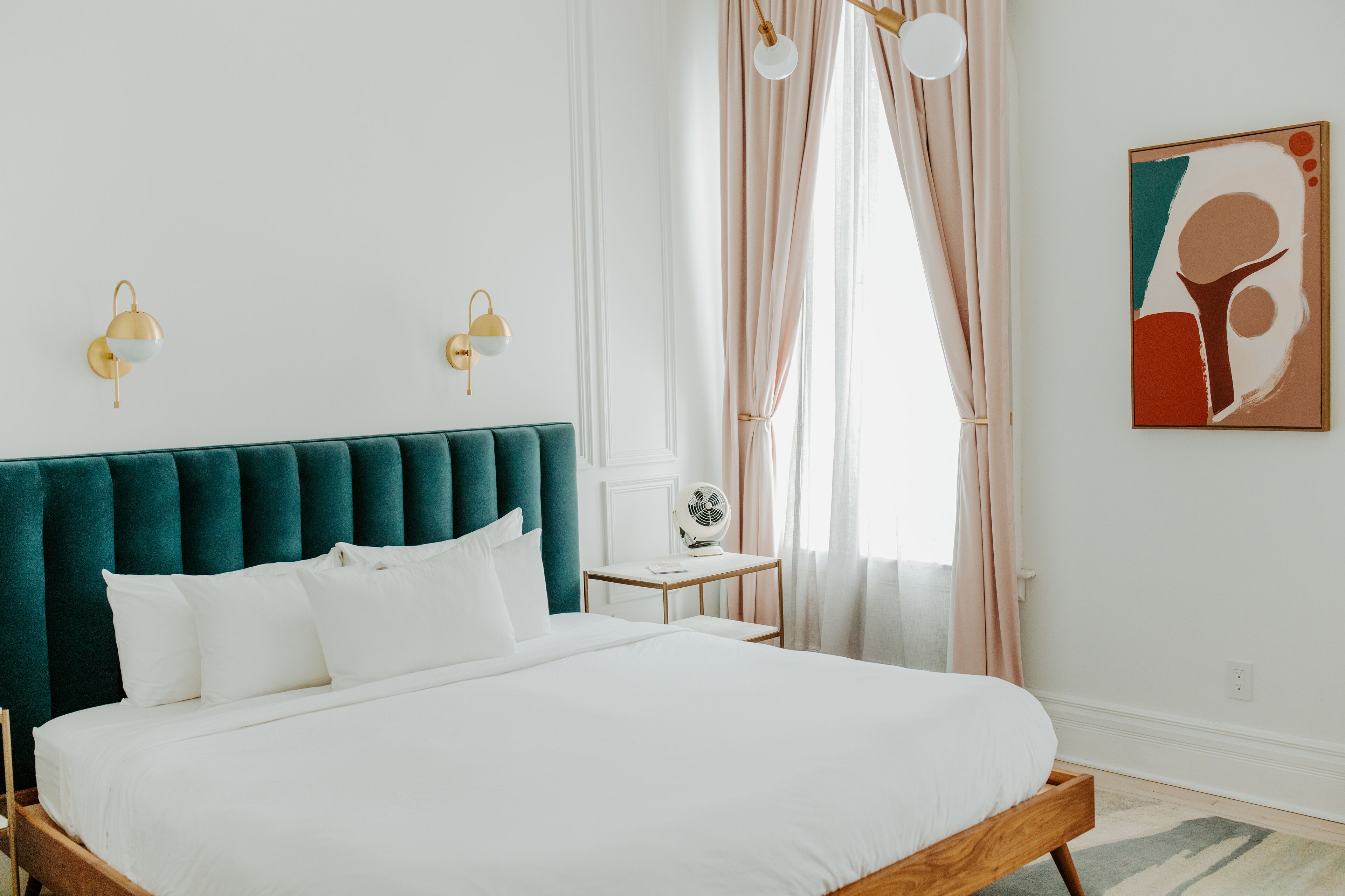 A neatly arranged bedroom with a large bed, a bedside table, and a wall-mounted fan.