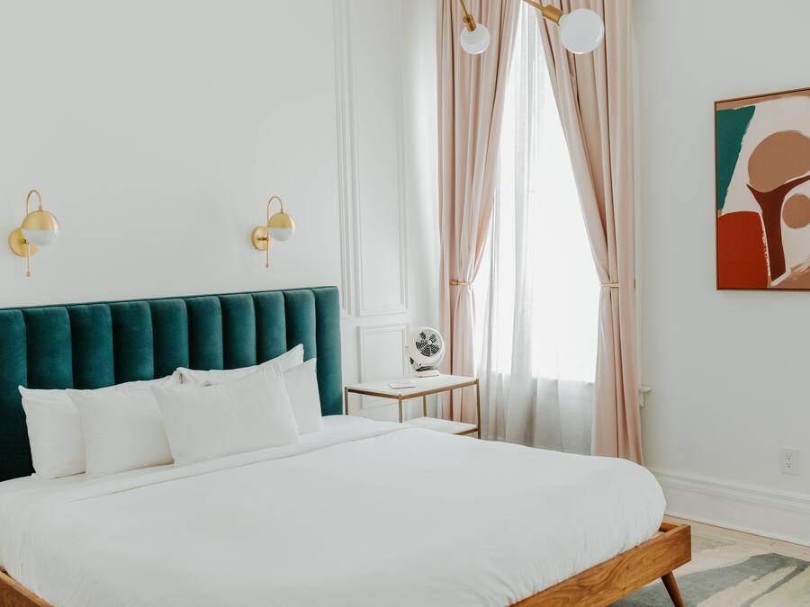 A neatly arranged bedroom with a large bed, a bedside table, and a wall-mounted fan.
