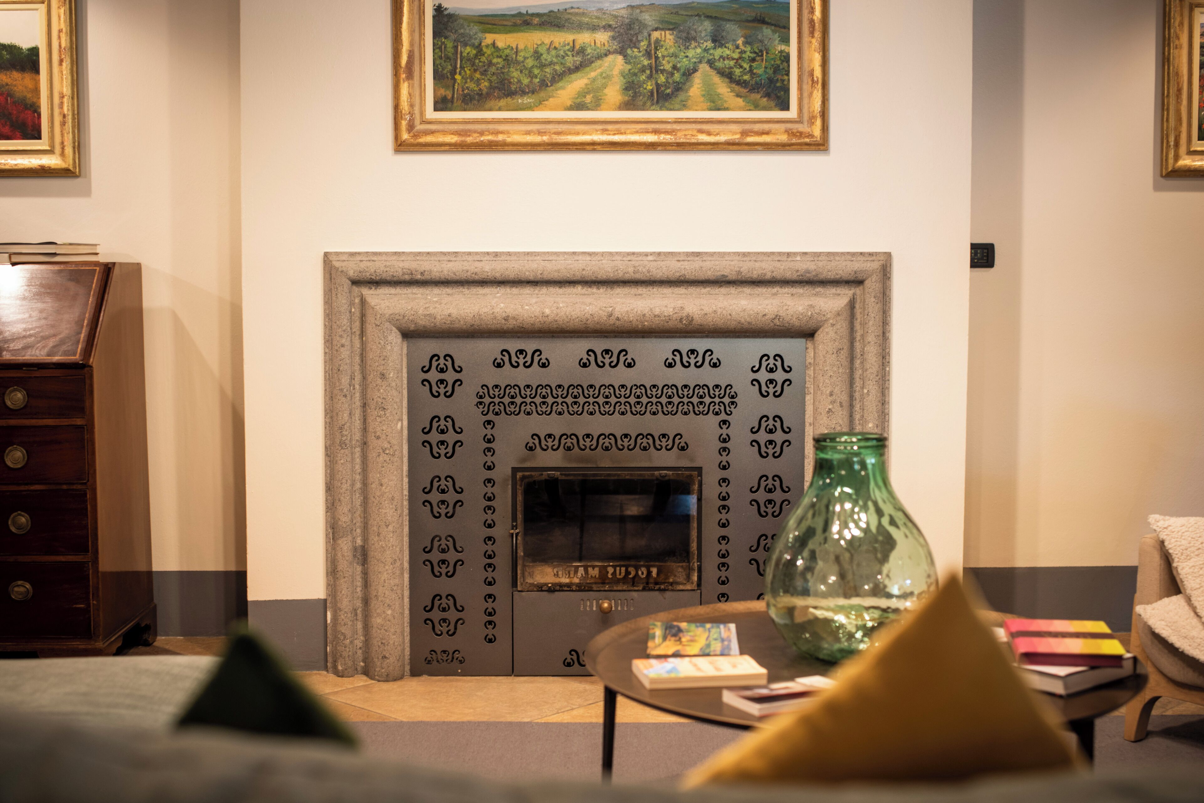 A room with a fireplace, a wooden dresser, a sofa, and a painting on the wall.