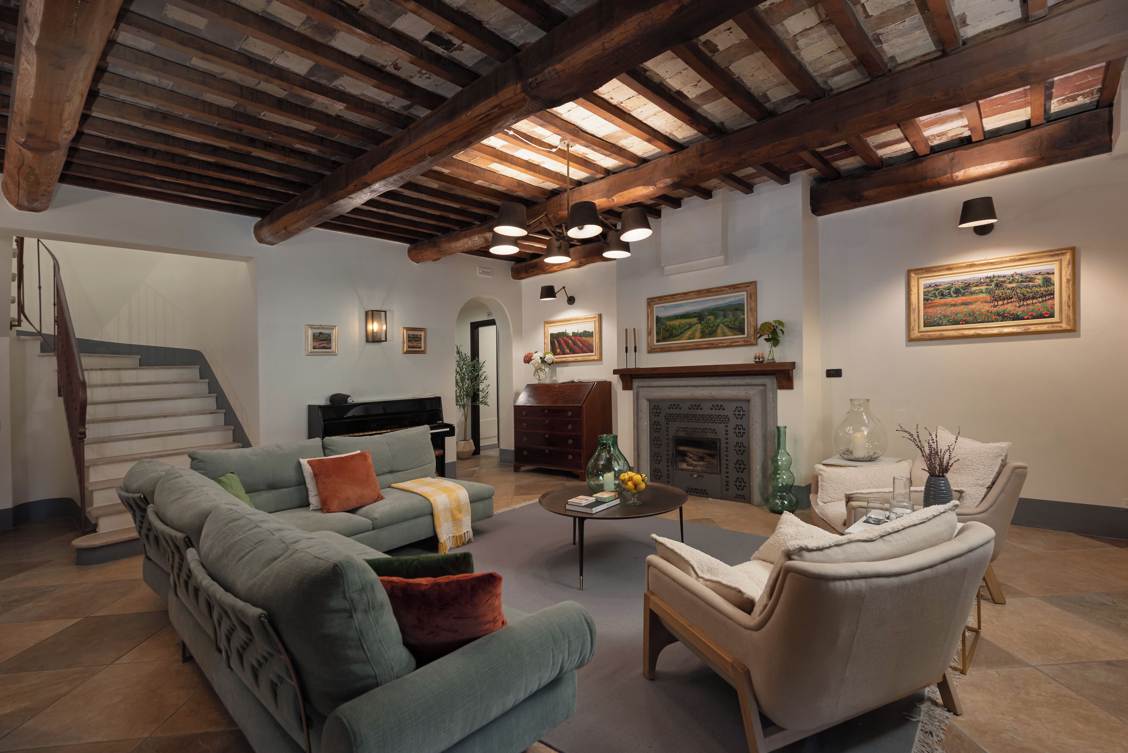 Amplia sala de estar con una imponente escalera, un piano y una chimenea.