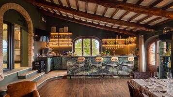 Eine Bar mit Marmorplatte, Barhocker und Blick ins Freie durch ein großes Fenster.